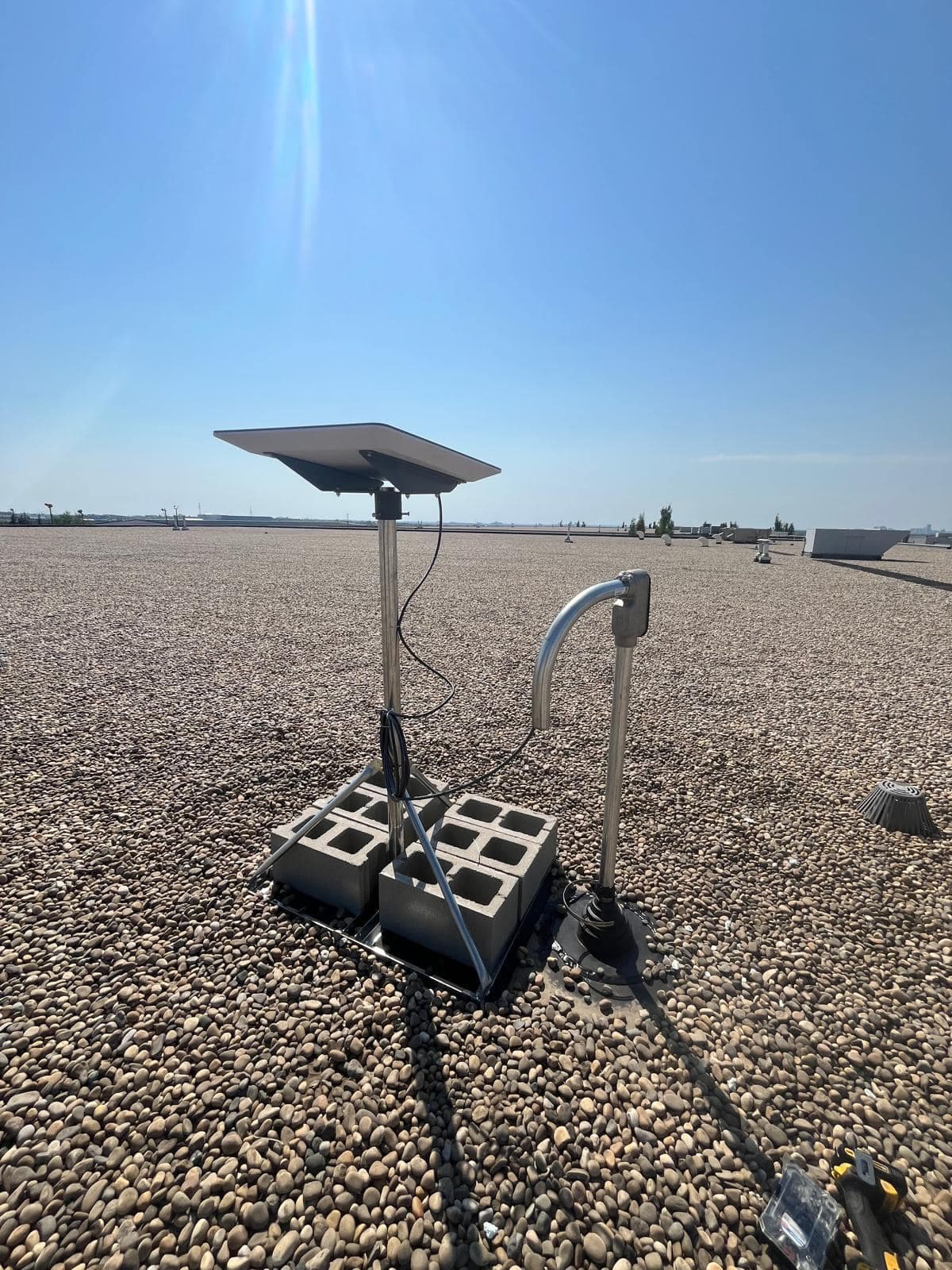 Starlink dish on a ballast frame with a galvanised conduit weatherhead curving into a sealed roof penetration